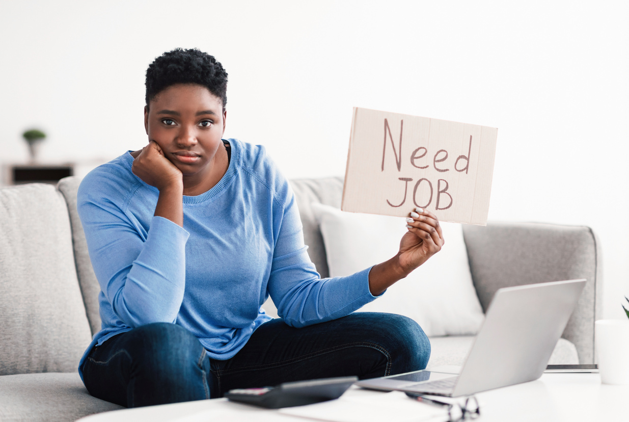 Young sad black woman holding sign Need job